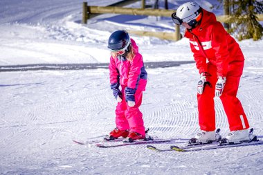 LAlpe DHuez, Fransa 02.01.2019 Profesyonel kayak hocası güneşli bir günde bir çocuğa dağ eteklerinde kayak yapmayı öğretiyor..
