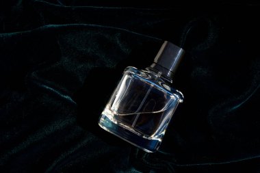 Bir şişe parfüm, arka planda koyu yeşil ve mavi renkli parfüm şişesi. Kapat.