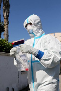 İtalyan hemşireler kendilerini koruyucu giysi, koruyucu maskeler ve eldivenlerle Puglia, İtalya 'da olası bir Coronavirus covid-19 vakası için evde örnek almak üzere hazırlıyorlar - 24 / 04 / 2020