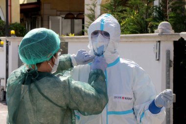 İtalyan hemşireler kendilerini koruyucu giysi, koruyucu maskeler ve eldivenlerle Puglia, İtalya 'da olası bir Coronavirus covid-19 vakası için evde örnek almak üzere hazırlıyorlar - 24 / 04 / 2020