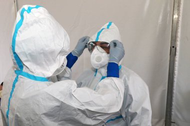 Koruyucu elbiseli, koruyucu maskeli ve eldivenli İtalyan hemşireler, Coronavirus covid-19 vakası nedeniyle vatandaşlara burun temizliği yapıyorlar.