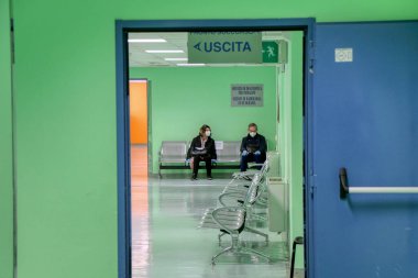 İki kişinin beklediği bir İtalyan hastanesinin yeşil bekleme odası. Puglia, İtalya