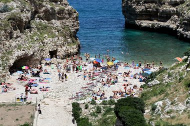 Polignano a Mare, Puglia, İtalya 'daki ünlü Lama Monachile plajında hamamlar ve turistler