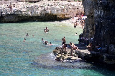 Polignano a Mare, Puglia, İtalya 'daki ünlü Lama Monachile plajında hamamlar ve turistler