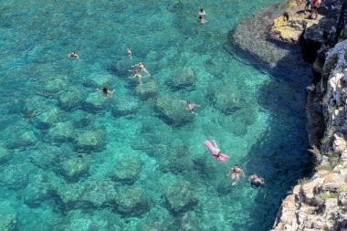Polignano a Mare, Puglia, İtalya 'daki ünlü Lama Monachile plajında hamamlar ve turistler