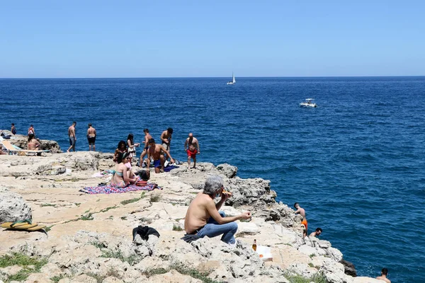 Polignano a Mare, Puglia, İtalya 'daki ünlü Lama Monachile plajında hamamlar ve turistler