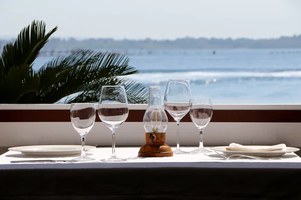 Table set in a restaurant in front of a window overlooking the sea