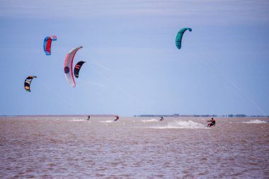 Bulutlu bir günde gölde birkaç uçurtma yelken açtı. Dört adam.