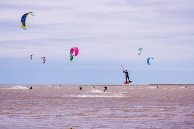 Bulutlu bir günde birkaç kişi uçurtma uçuruyor. Havadaki adam.