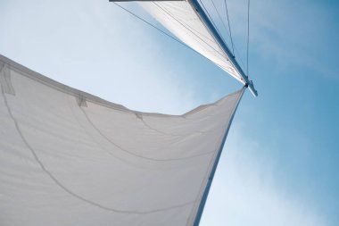 Mavi gökyüzüne karşı denizde bir yatta yelken açmak.