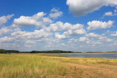 Göl ve gökyüzünde beyaz kabarık bulutlarla sonbahar manzarası