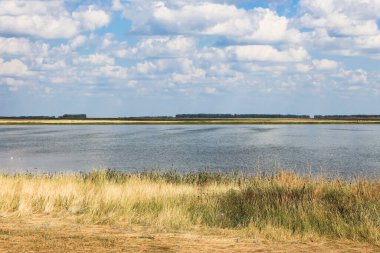 Göl ve gökyüzünde beyaz kabarık bulutlarla sonbahar manzarası