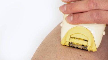 Elektrikli epilatörle bacaklarındaki kılları alan bir kadının yakın çekimi. Güzellik konsepti, kaplıca, vücut bakımı