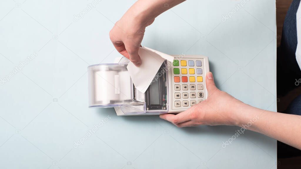 Hands of a young woman tearing a check from the cash register after purchasing a product, entering discounts into a store. Business idea, trade