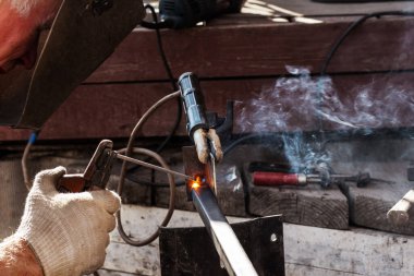 Koruyucu metalle kaynak yapma kavramı. Koruyucu maskeli bir adam, sabit demir yapıların yay döşemesiyle meşgul..