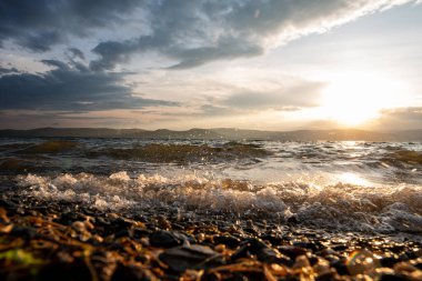 Fırtınalı bir gölün üzerinde gün batımında büyük dalgaların suları. Köpüklü ve spreyli büyük dalgalar. Uzakta güzel dağlar görülebilir. Turgoyak Rusya 'sı. Güzel doğa arkaplanı