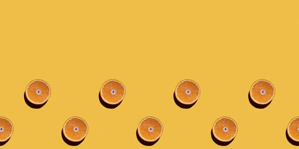 Modello senza cuciture di frutta variopinta di metà di arance su uno sfondo giallo. Vista dall'alto, copia spazio — Foto Stock