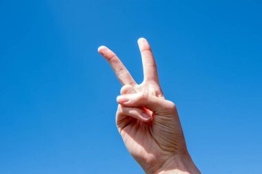 İki numaralı jest sembolü. Mavi gökyüzünde zafer ya da barış jesti gösteren Kafkas bir kadının iki parmağı