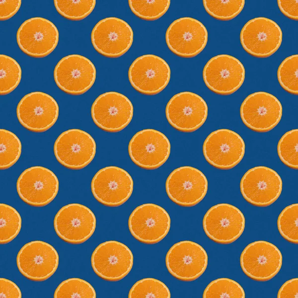 Seamless pattern of half orange isolated on a classic blue background. Minimal, food texture, fruit background.