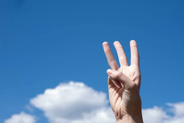 Zbliżenie Dłoni Kobiety Pokazujące Trzy Palce Odizolowane Tle Błękitnego Nieba — Zdjęcie stockowe