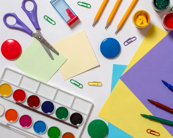 Stationery for study at school lies on blue. Back to school. Books and textbook, apple material for creativity. Top view.