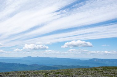 Stratocumulus bulutları gökyüzünde bir dağ platosuna yayılıyor, uzaktaki mavi dağlar. Kümülüs bulutları doğada. Doğa arka planı, duvar kağıdı, kartpostal
