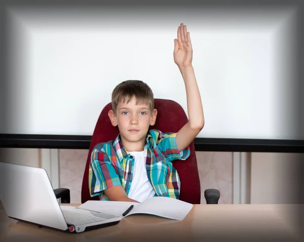 Un chico listo y lindo levanta la mano para responder en clase. Niño feliz contra una pizarra blanca. Concepto educativo — Foto de Stock