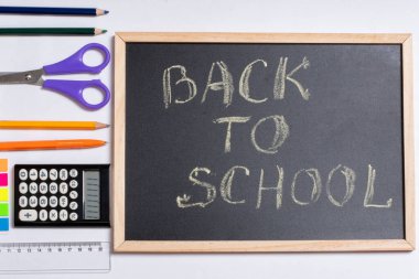 Yaratıcı düz görünüm, okul konseptine, eğitim konseptine dayanıyor. Renkli okul malzemeleri ve siyah karatahta