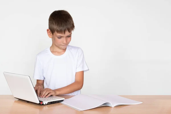 Chico Lindo Sienta Una Mesa Imprime Portátil Mira Cuaderno Libro — Foto de Stock