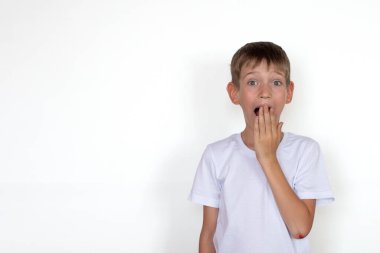 Beyaz tişörtlü, beyaz arka planda izole edilmiş sarışın çocuk. Beyaz tahtaya karşı mutlu çocuk. Eğitim konsepti, okula dönüş, çocuk duyguları.