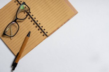 Beyaz arka planda izole edilmiş kalem ya da kalem ve gözlüklü açık defterin üst görünümü. Düz konum, kopyalama alanı. İş konsepti