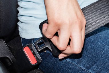 Beyaz bir kadının, arabaya bağlanmak için kemer tokası tutarken yakın çekimi. Seçici odak, uzayı kopyala. Araba güvenliği kavramı