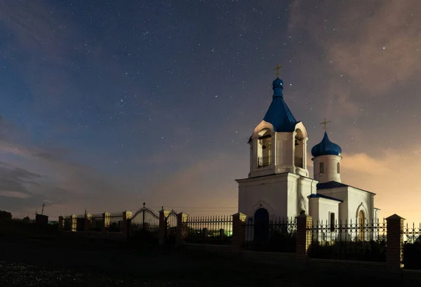 Bílý křesťanský kostel na pozadí noční oblohy. Lze použít jako pozadí, pohlednici, malbu — Stock fotografie