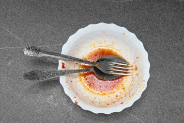 Üst kattaki çatal ve kaşık beyaz kirli tabakta yatıyor, gri arka plan, kopyalama alanı. Yemekten sonra kirli bulaşıklar.