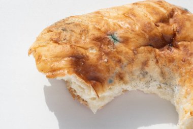 Beyaz arka planda küflü bozuk bir ekmek parçasına yakın plan, kopyalama alanı. Bozuk yemek kavramı, tehlikeli yiyecekler. Gıda paylaşım kavramı