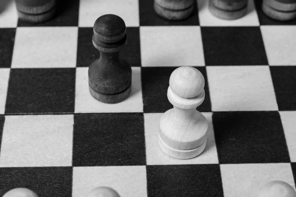 The first move in chess was made by pawns to meet each other. Chess game start, close-up, selective focus black and white. Business concept start of business negotiations, business cooperation