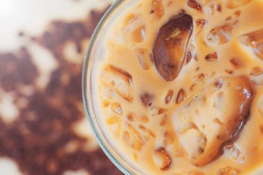 Arka plan için ahşap bir masaya yerleştirilmiş buzlu kahvenin, yanında kahve çekirdekleri bulanıklaştırılmış buzlu kahvenin en alttaki görüntüsü kahve ürünleri için bir reklam oluşturmak için kullanılır..