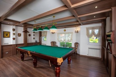 Bilardo odasının içi. Oyun için yeşil masa. Eski Alman tarzı tasarım. Tavanda, duvarlarda ve yerde kahverengi ahşap dekoru var..