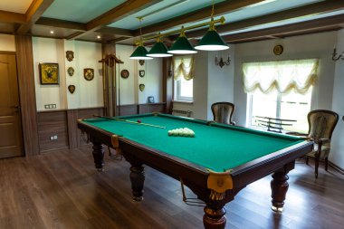 Bilardo odasının içi. Oyun için yeşil masa. Eski Alman tarzı tasarım. Tavanda, duvarlarda ve yerde kahverengi ahşap dekoru var..