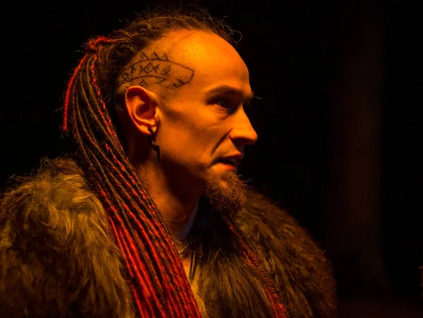 Irdorath group, clip making backstage. The caucasian man with dreadlocks,  clothed in fur. Viking\'s nighttime in the forest is lighting by flamed torches.