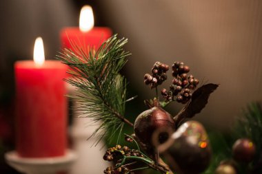 İki kırmızı mum ve yeşil ladin çelengi ile süslenmiş Advent kartı. Noel sahnesi. Kahverengi arkaplanda boşluk kopyala.