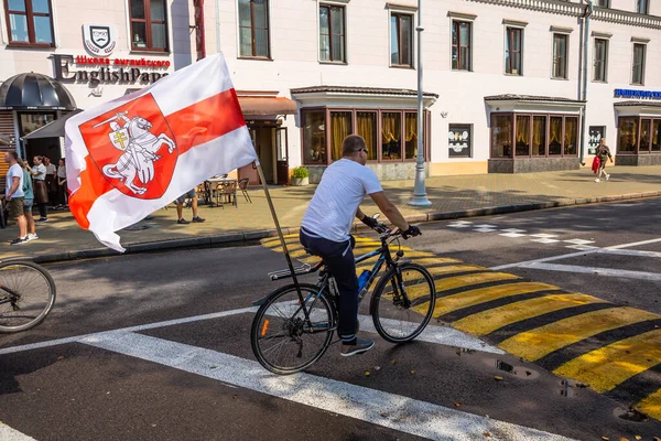 MINSK, BELARUS - 30 Ağustos 2020. Baskılara, şiddete ve cumhurbaşkanlığı seçim sonuçlarına karşı barışçıl protestolar. Büyük bayraklı bisikletli adam..