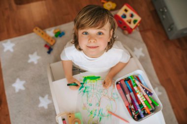 Sarışın çocuk evde resim yapıyor. Karantina sırasında eğlence. Koronavirüsteki aile.