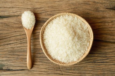 ahşap zemin üzerine kaşıkla hasır sepet içinde beyaz pirinç