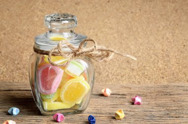 jöleli şeker tatlı ahşap arka plan üzerinde cam şişede