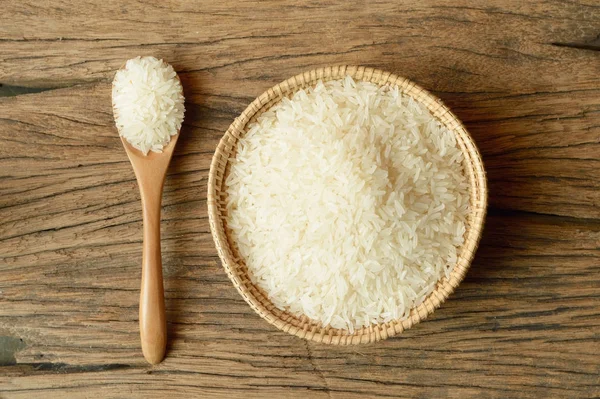 ahşap zemin üzerine kaşıkla hasır sepet içinde beyaz pirinç