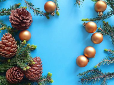 Taze yeşil köknar, kozalak ve mavi bir masanın üstünde altın toplar. Noel ve Yeni Yıl Düzlüğü, en iyi manzara. Davetiye ya da tebrik kartı tasarımının modeli, Noel dekorasyonlu ürün arkaplanı