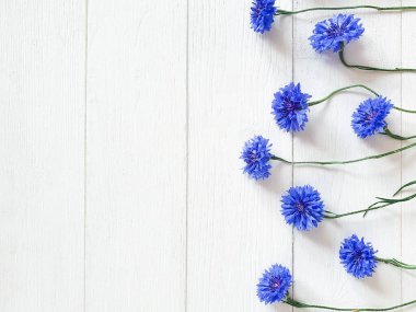 Çiçeklerin en üst köşesindeki mavi çiçekleri eski püskü beyaz ahşap arka planda görebilirsiniz. Çiçek çizgisi, düz çizgi, yatay fotoğraf.