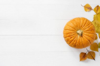 Turuncu / sarı balkabağı manzarası ve köhne beyaz tahta arka planda sonbahar sarı yaprakları. Sonbahar, sonbahar, Cadılar Bayramı konsepti. Trend gölgesi, kopyalama alanı, düz yatış.