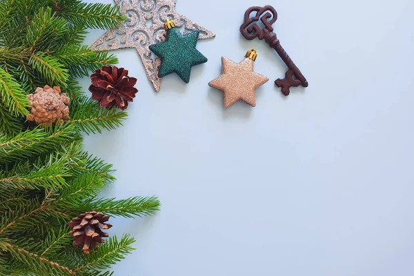 Fir borders, stars, iron key and pine cones on a pastel blue background. Top view of Christmas frame, place for your text or product. Close-up, Christmas flat lay